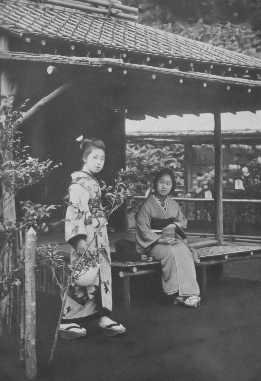 a black and white photo of two women sitting on a bench