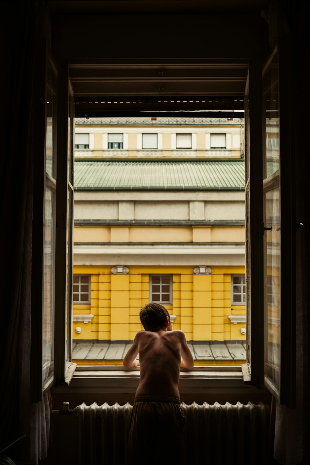 a person looking out a window at a yellow building