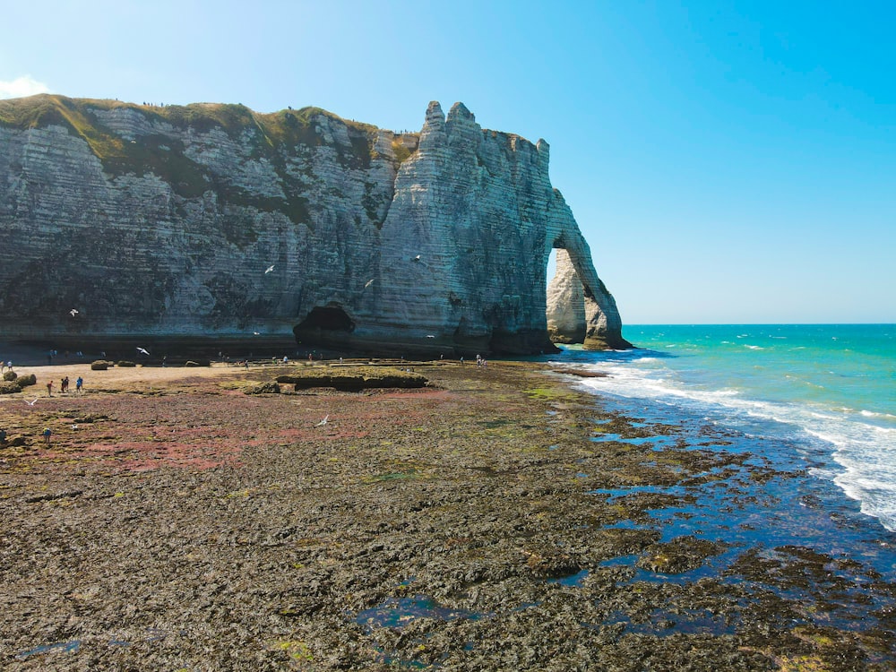 a beach with a large rock formation next to the ocean