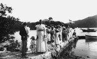 Historic group photo of local sailors in traditional gear gathered on the pier.