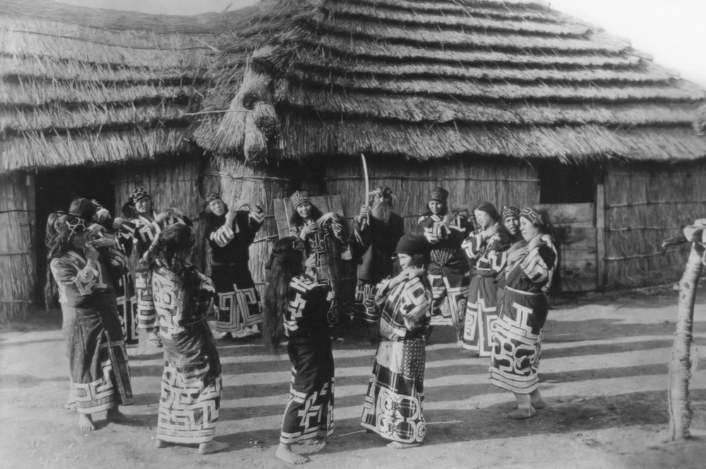a group of people standing in front of a hut