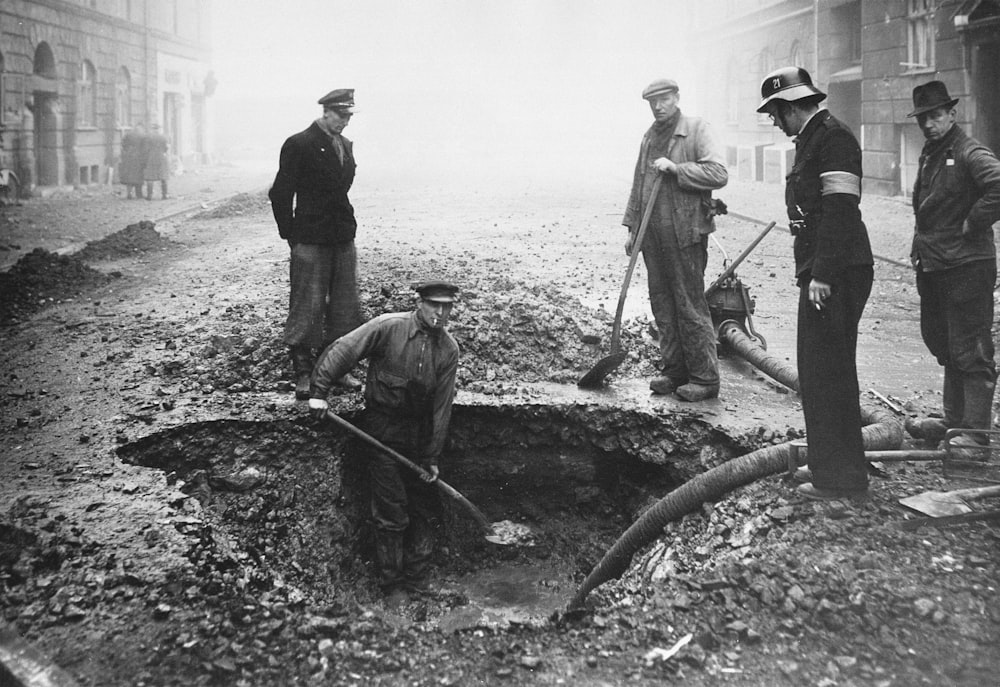a group of men standing around a hole in the ground