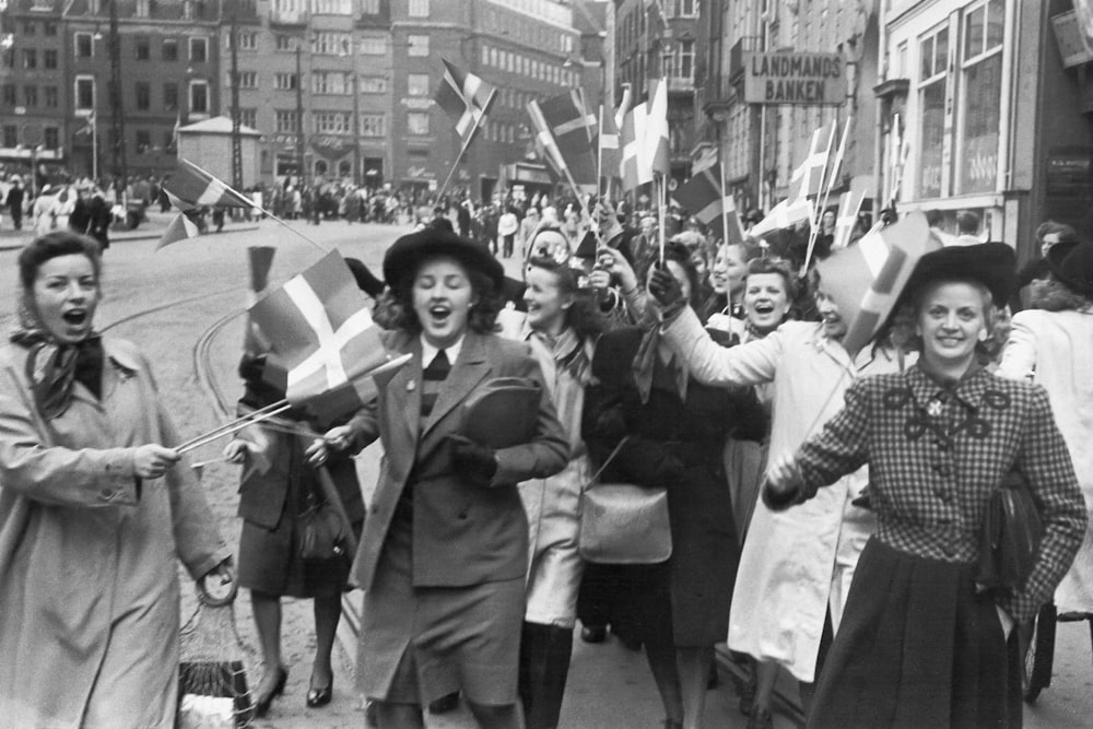 a group of women walking down a street holding flags