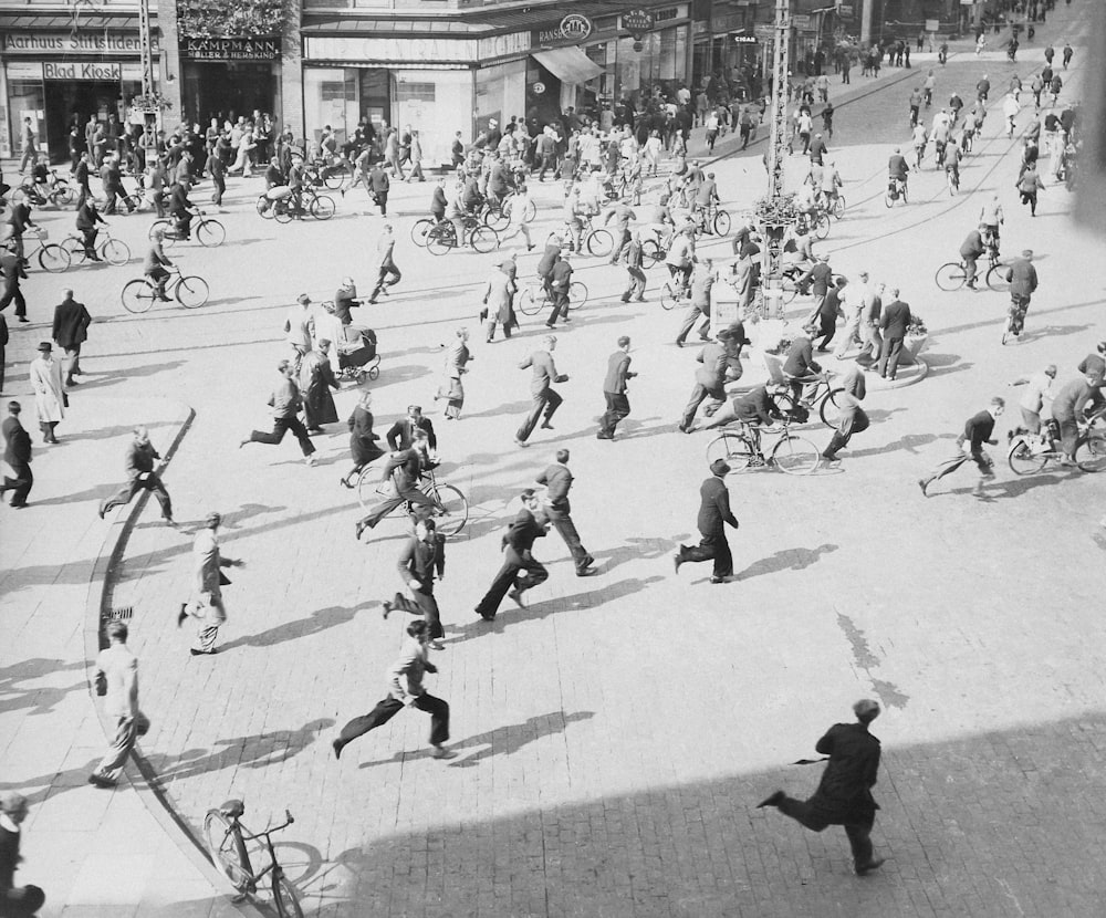 a crowd of people walking down a street next to tall buildings