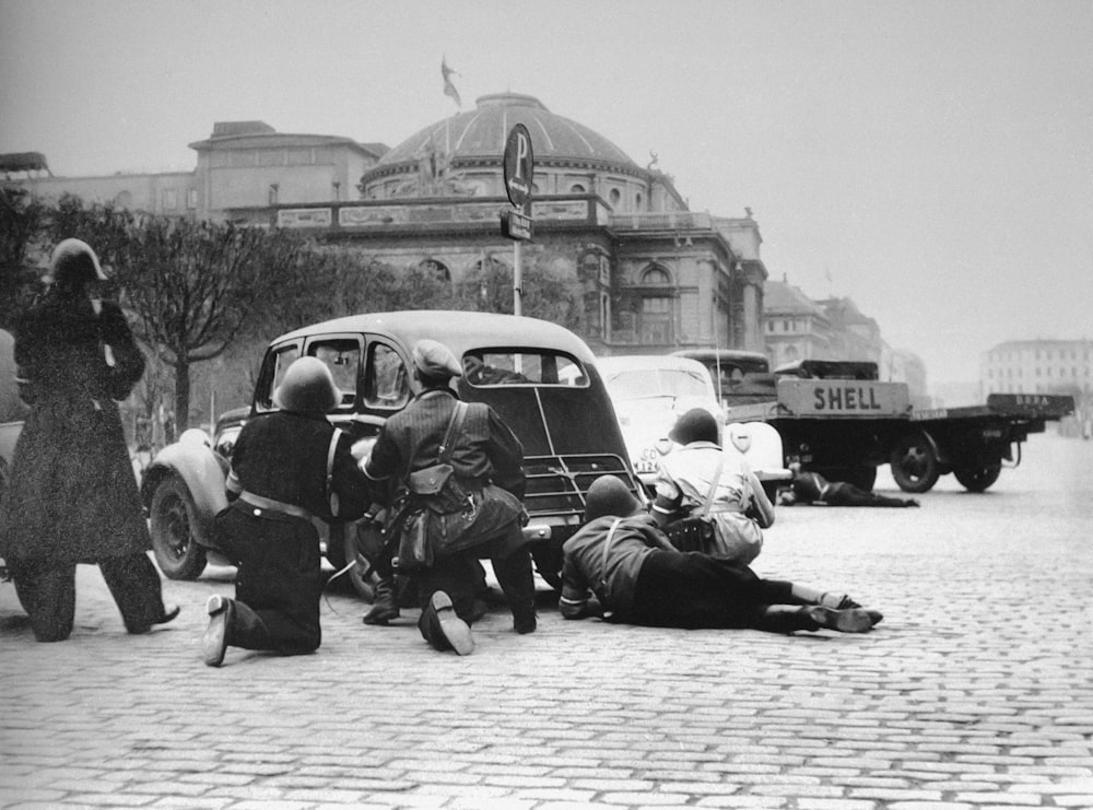 a group of people sitting on the ground next to a car