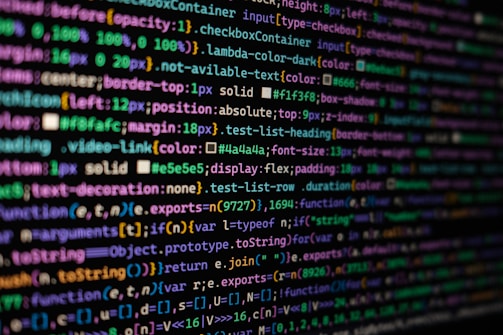 The image features colorful lines of code on a computer screen, showcasing various syntax elements with different colors to highlight keywords, values, and functions. The background is dark, enhancing the visibility of the text.