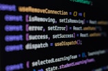 Computer screen displaying lines of JavaScript code. Variables and methods appear, with syntax highlighting in different colors such as purple, yellow, blue, and white against a black background.