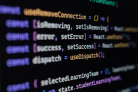 Computer screen displaying lines of JavaScript code. Variables and methods appear, with syntax highlighting in different colors such as purple, yellow, blue, and white against a black background.