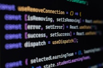 Computer screen displaying lines of JavaScript code. Variables and methods appear, with syntax highlighting in different colors such as purple, yellow, blue, and white against a black background.