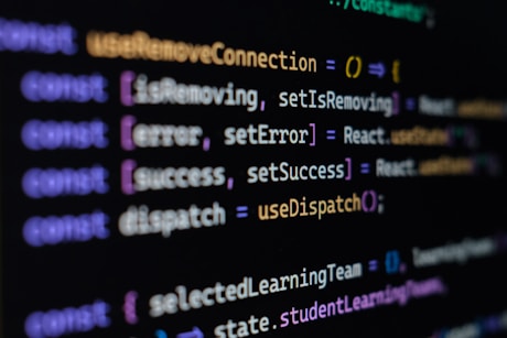 Computer screen displaying lines of JavaScript code. Variables and methods appear, with syntax highlighting in different colors such as purple, yellow, blue, and white against a black background.