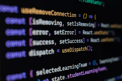 Computer screen displaying lines of JavaScript code. Variables and methods appear, with syntax highlighting in different colors such as purple, yellow, blue, and white against a black background.