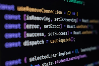 Computer screen displaying lines of JavaScript code. Variables and methods appear, with syntax highlighting in different colors such as purple, yellow, blue, and white against a black background.