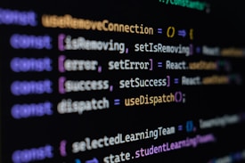 Computer screen displaying lines of JavaScript code. Variables and methods appear, with syntax highlighting in different colors such as purple, yellow, blue, and white against a black background.