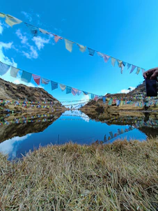 A serene Qinghai lake reflecting colorful prayer flags fluttering in the mountain breeze.