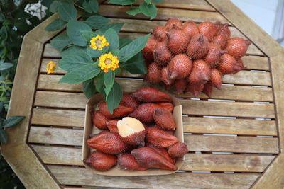Close-up of fresh Genipa americana fruits and leaves on a rustic wooden table.