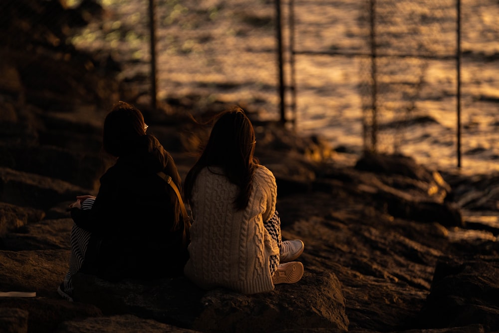 a couple of people sitting on top of a rock