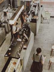 A small café counter with coffee cups and a cashier recording expenses.