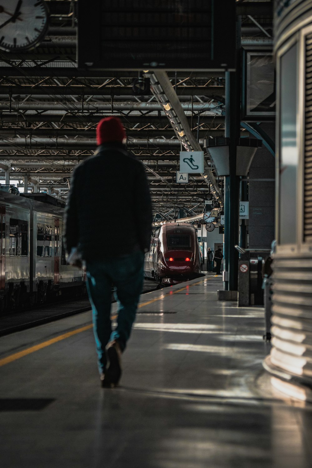 a man walking down a train station next to a train