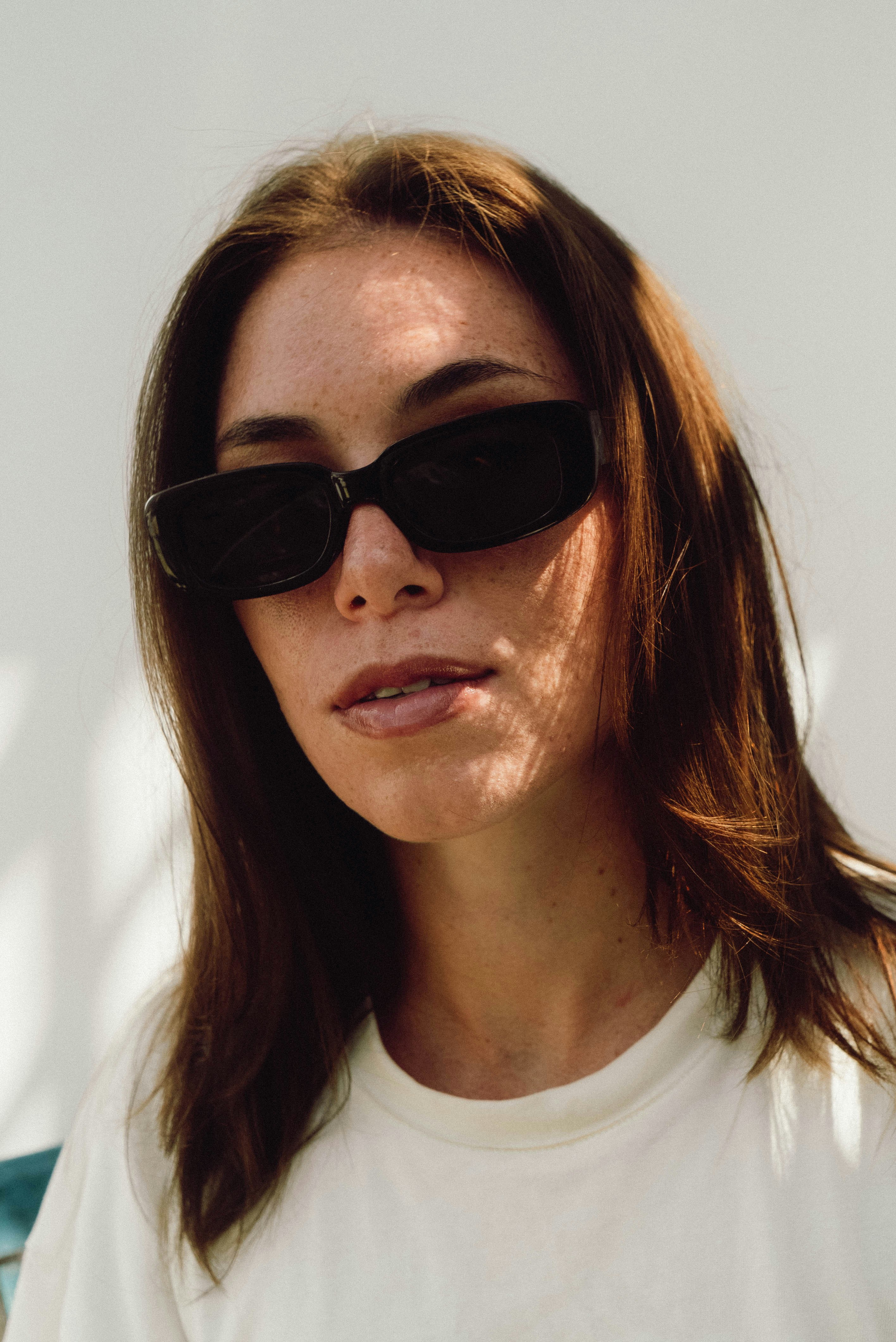a woman wearing sunglasses and a white shirt