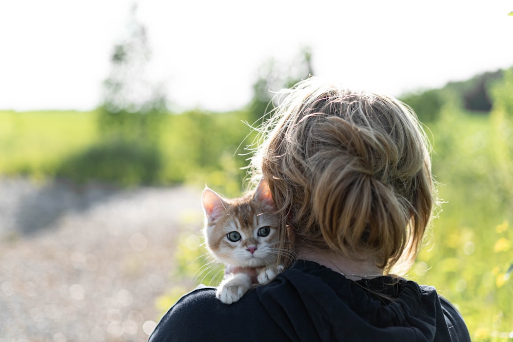 a woman holding a small kitten in her arms