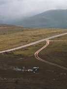 A rugged campsite at dawn with a tent, campfire, and gear laid out on a tarp