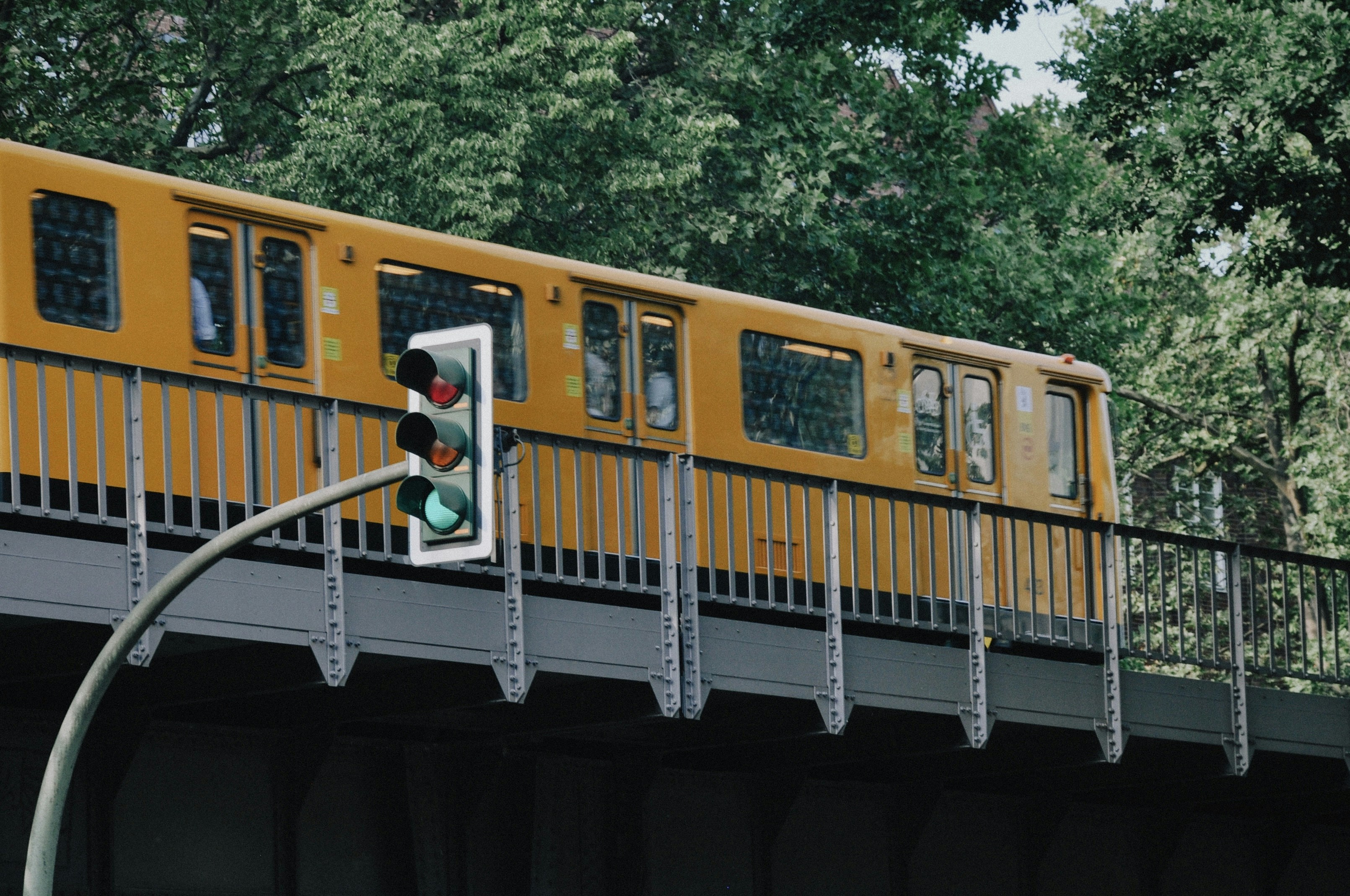 a yellow train traveling over a bridge next to a forest