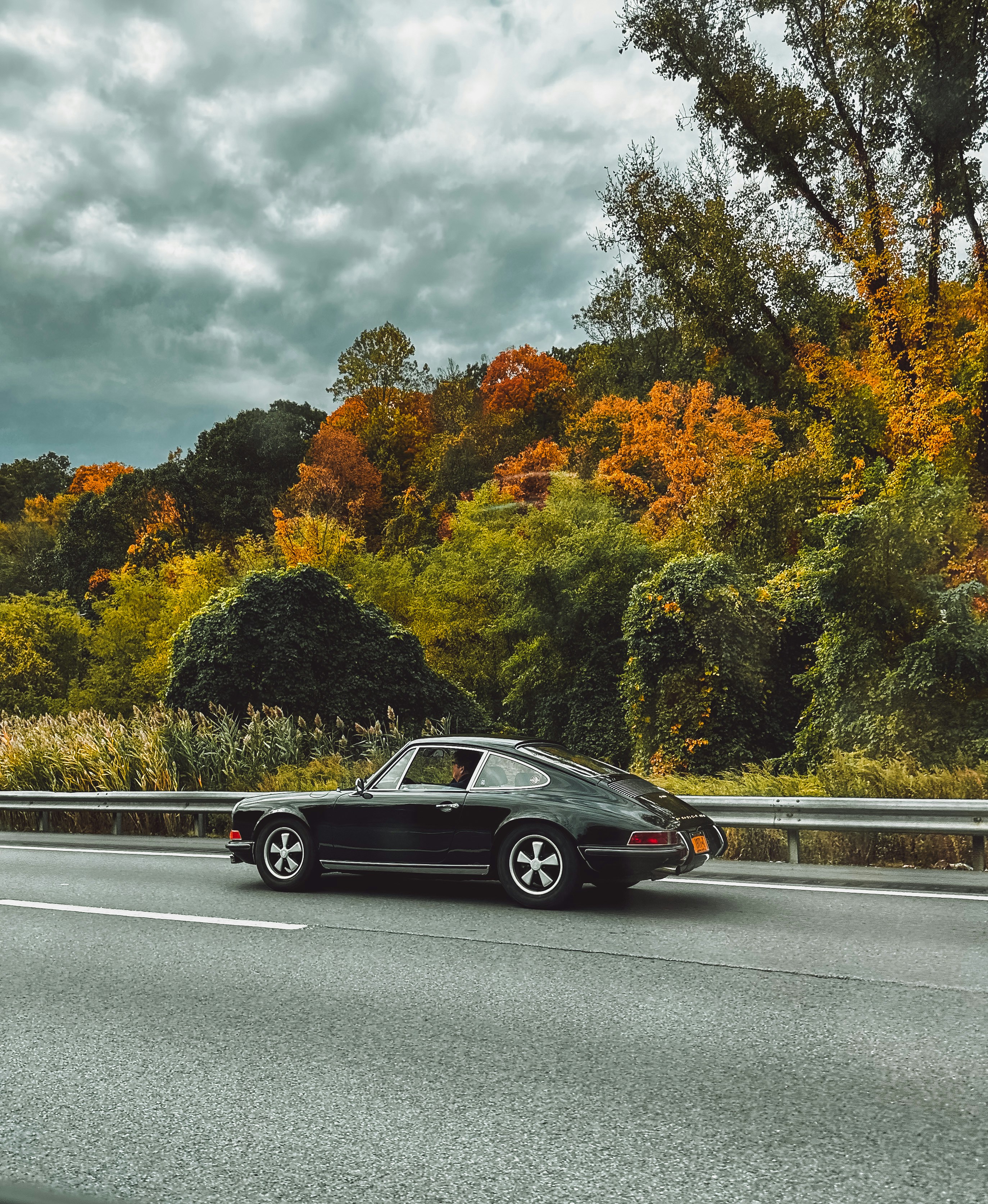 a black car driving down a road next to a forest