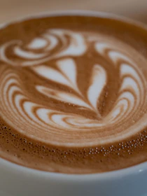 Close-up of a beautifully crafted latte with intricate foam art on top.