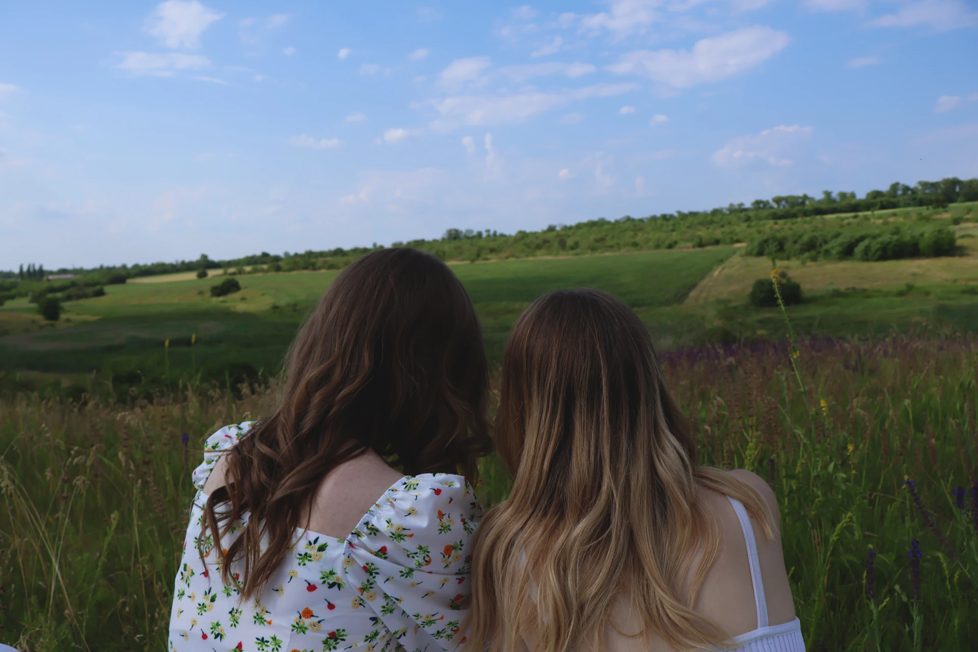 two women sitting in a field looking at the sky