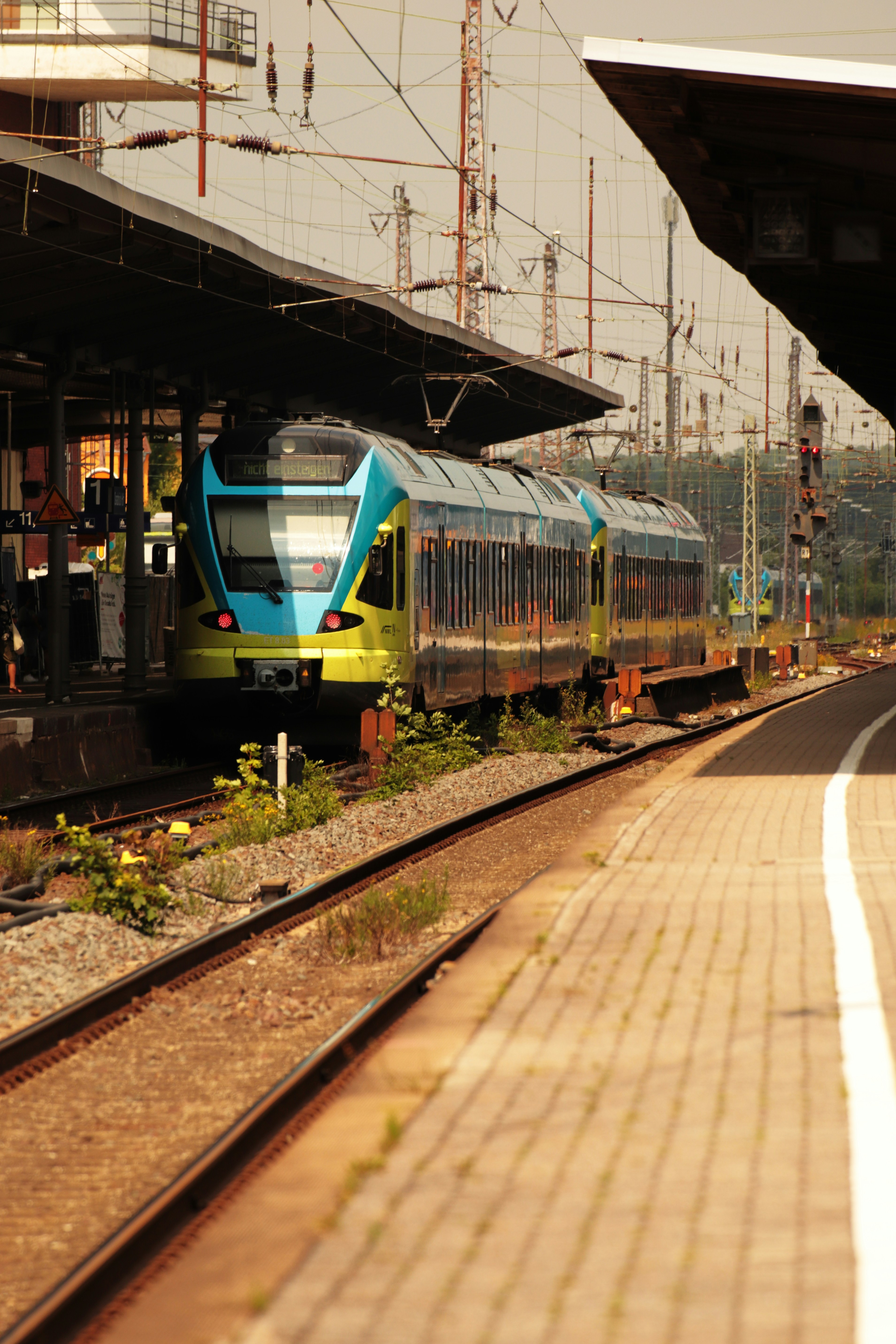 a blue and yellow train traveling past a train station