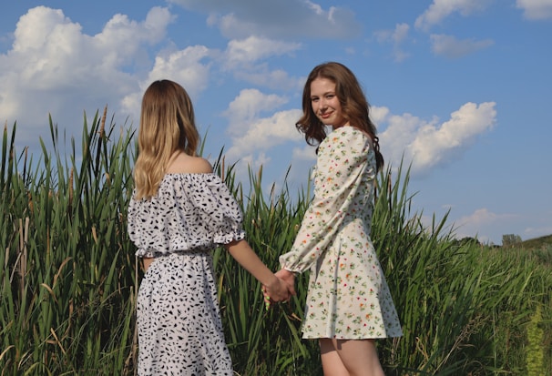 Group of women smiling and holding hands outdoors.