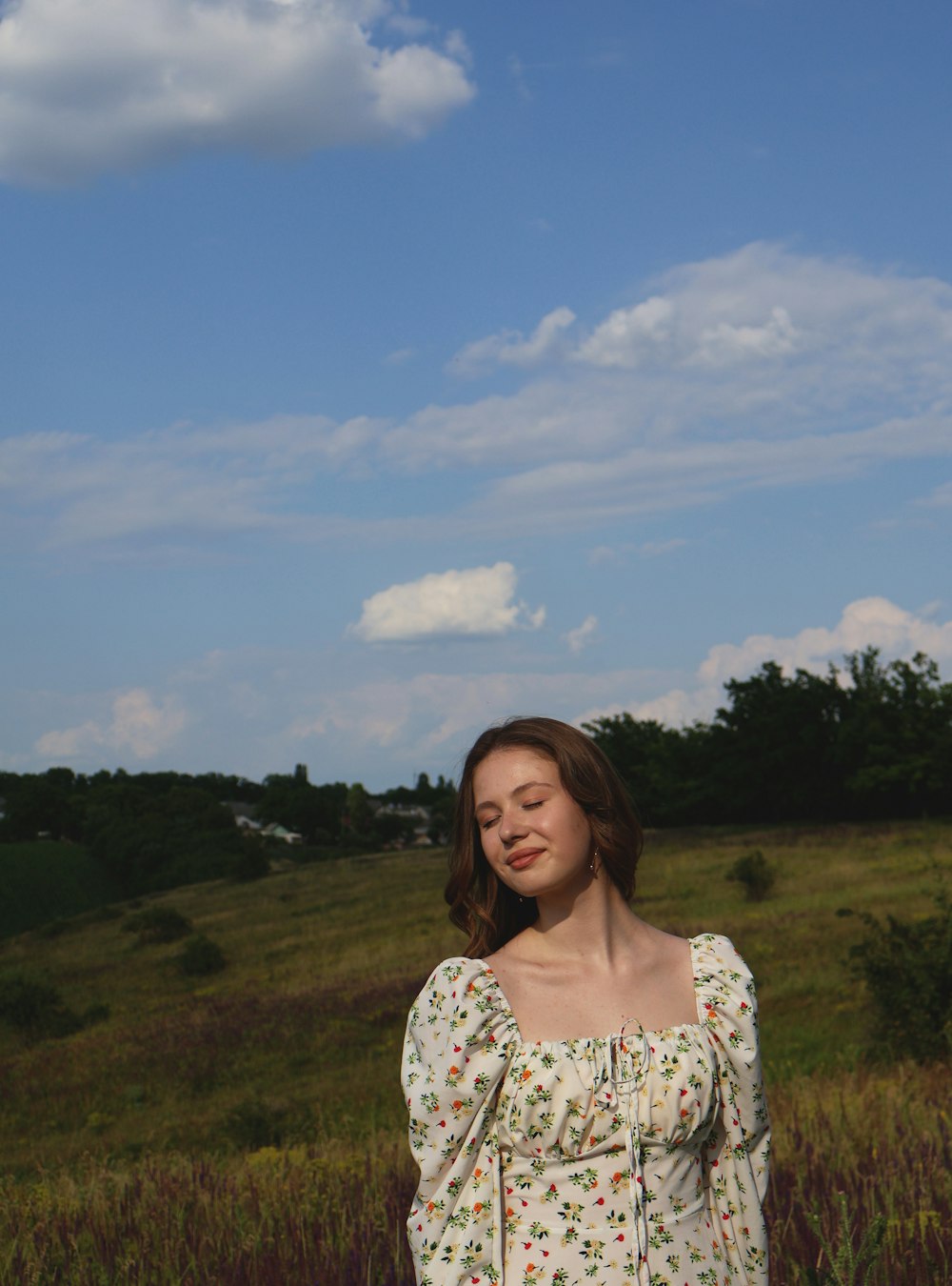 a woman standing in a field with her eyes closed