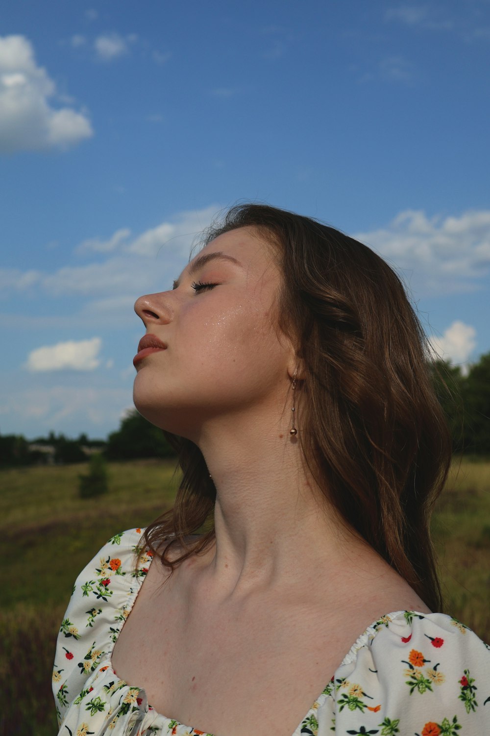 a woman standing in a field with her eyes closed