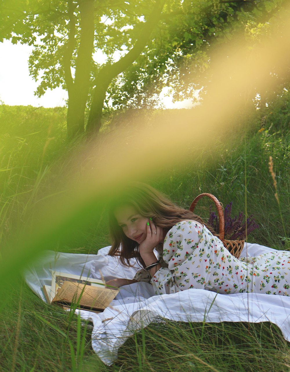 a woman laying in the grass reading a book