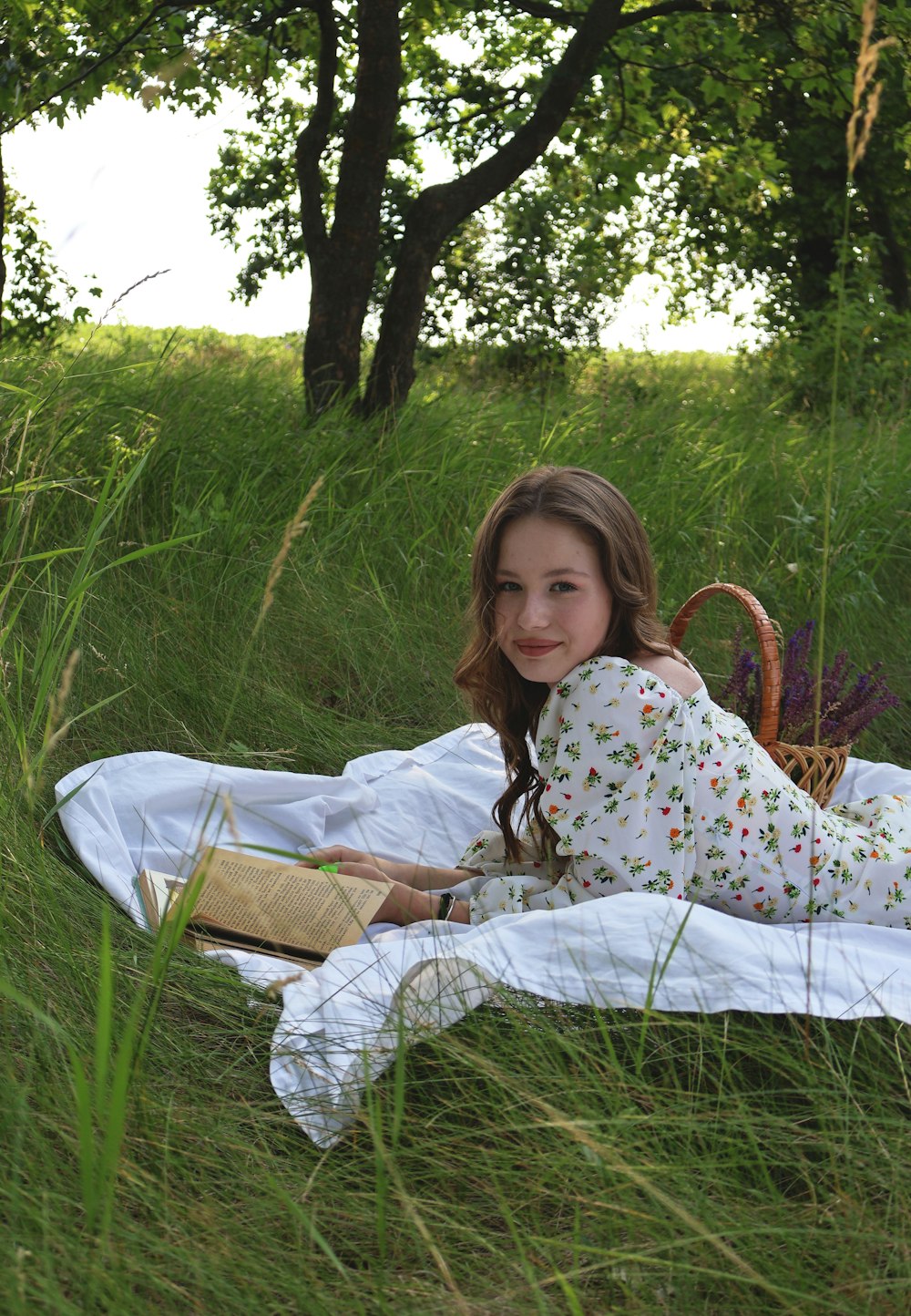 a girl laying in the grass reading a book