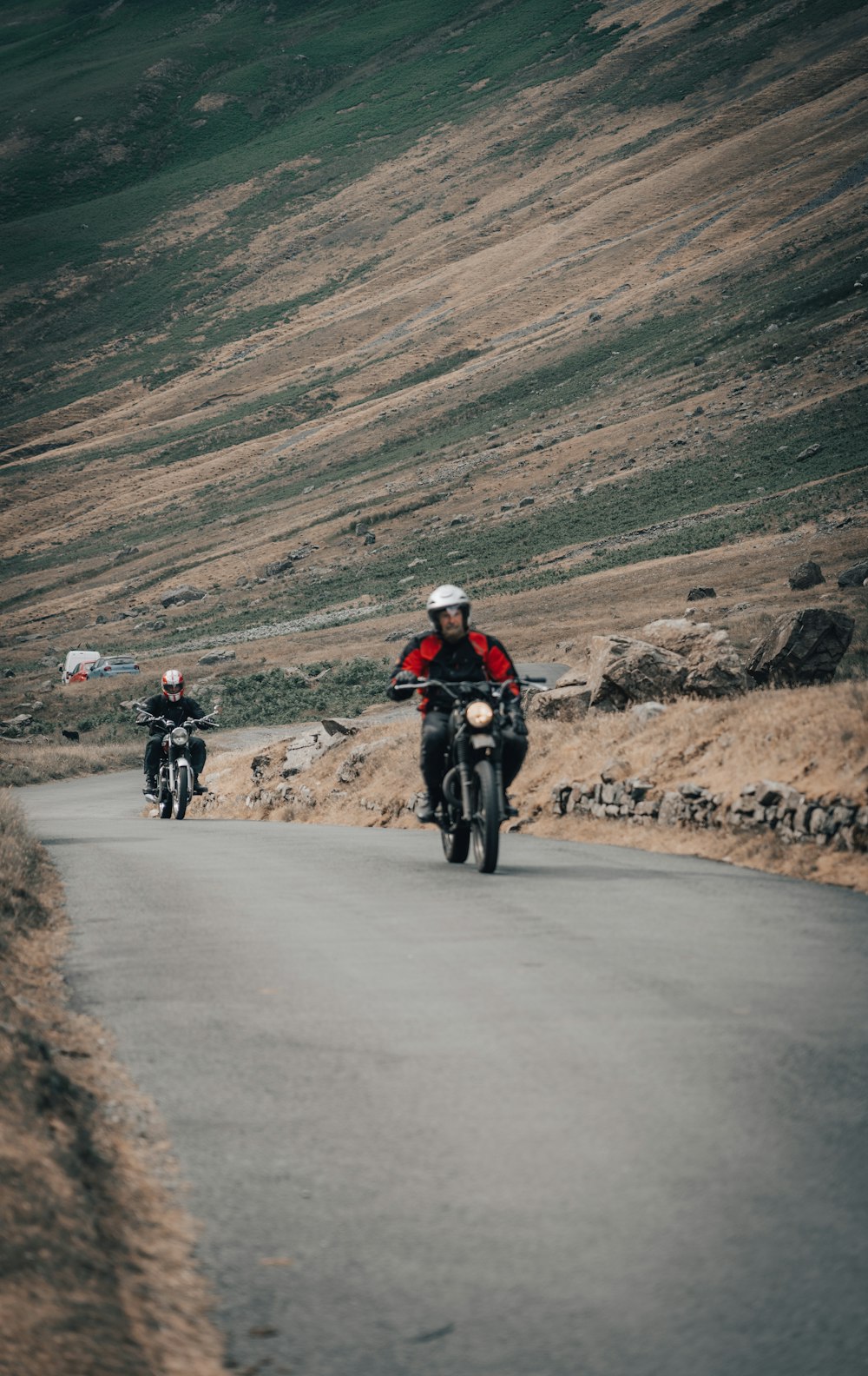 a couple of people riding motorcycles down a road