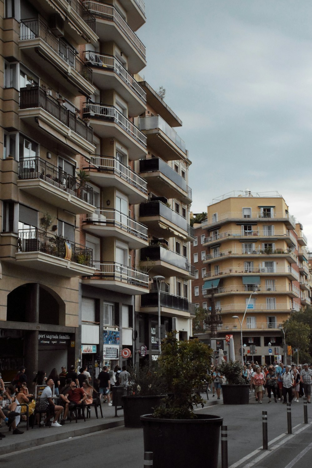 a group of people walking down a street next to tall buildings