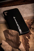 a black phone case sitting on top of a wooden table