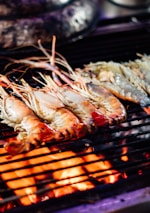 Close-up of sizzling shrimp on a hot grill with smoke rising.