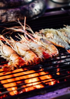 Close-up of sizzling shrimp on a hot grill with smoke rising.