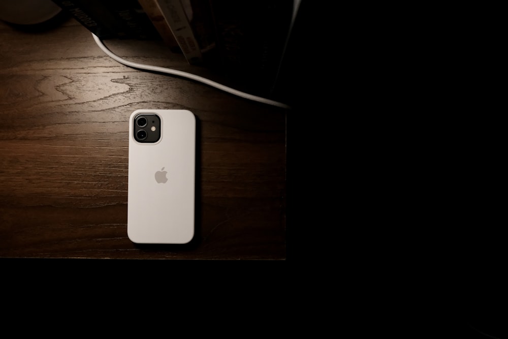 Un iPhone bianco seduto sopra un tavolo di legno