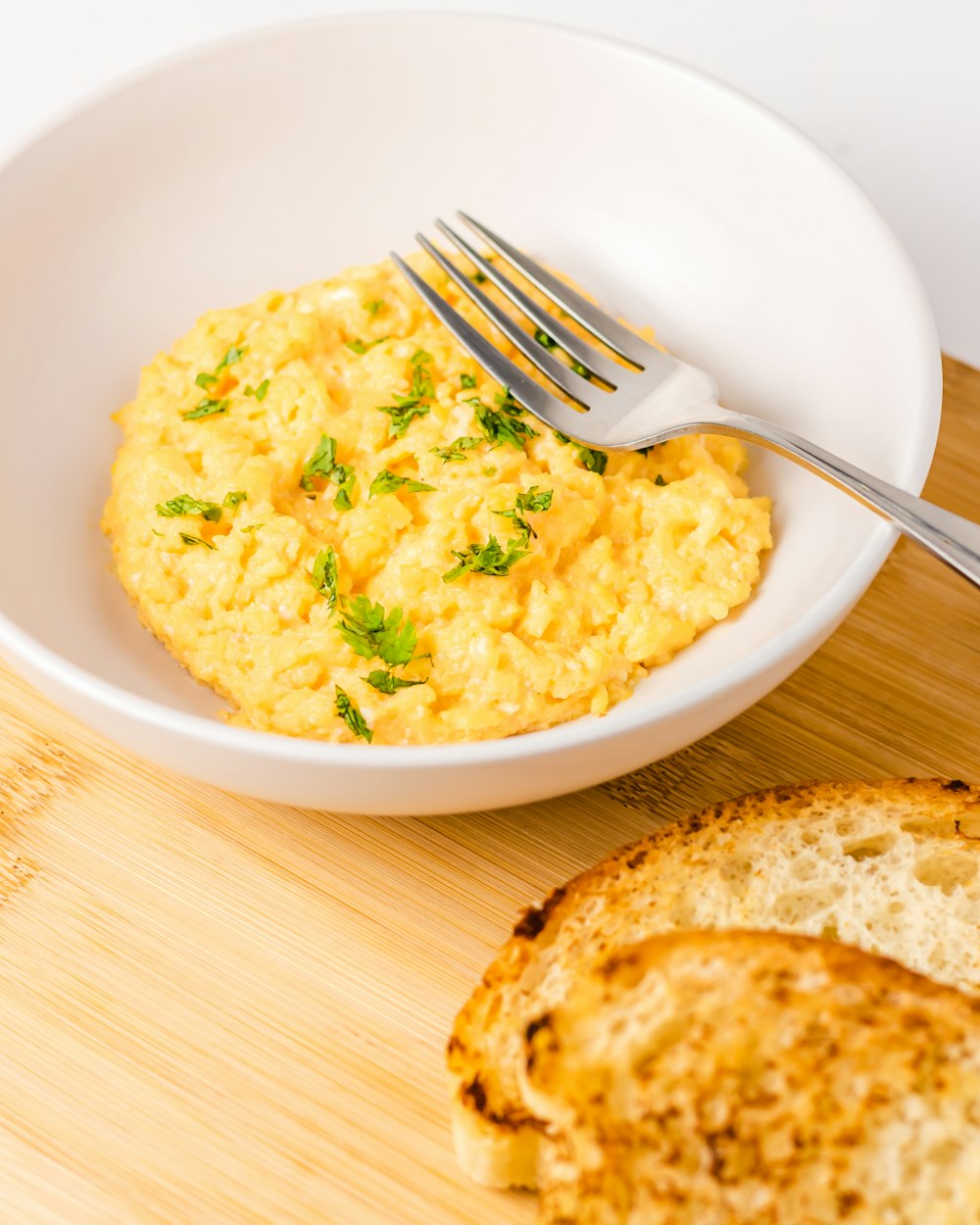 a bowl of scrambled eggs next to a slice of bread