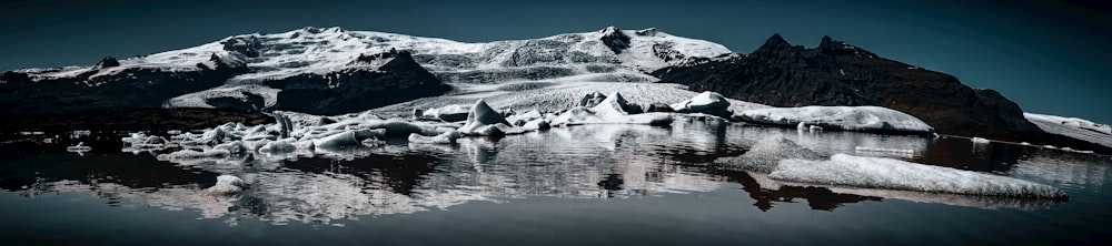 a snow covered mountain reflected in a body of water