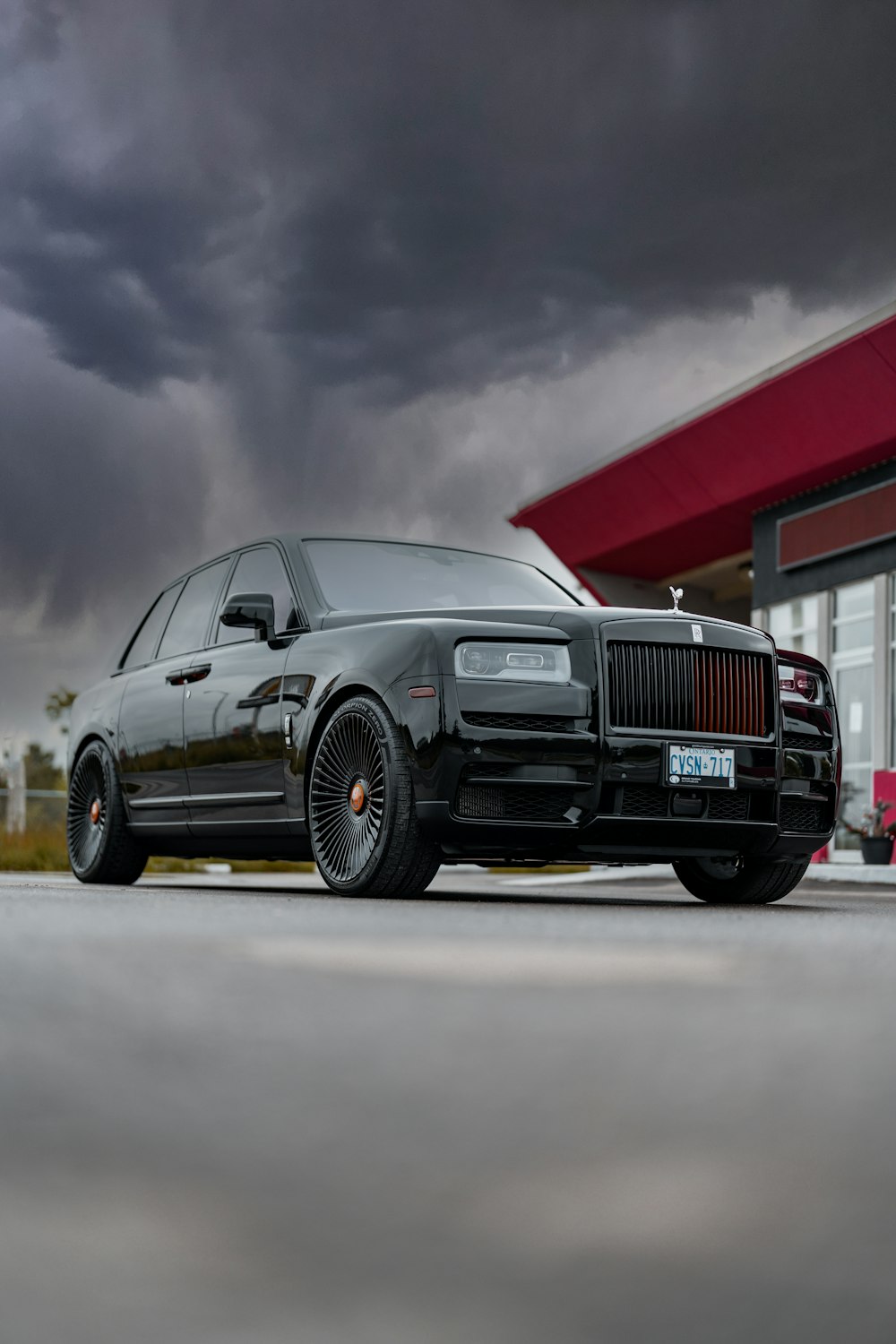 a black rolls royce parked in front of a gas station