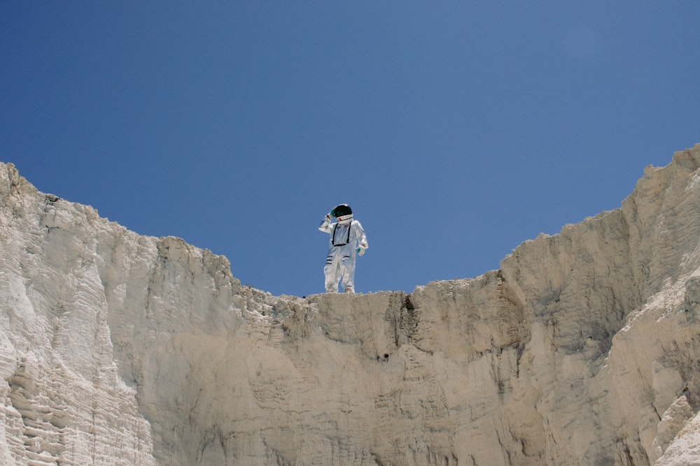 a man in a space suit standing on top of a cliff