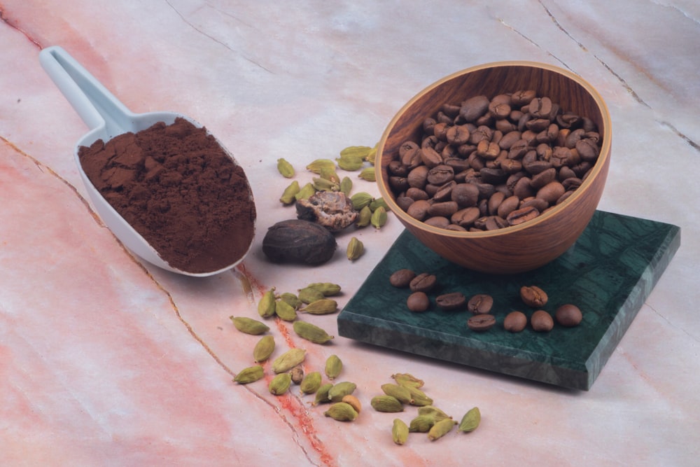 a wooden bowl filled with nuts next to a scoop of cocoa