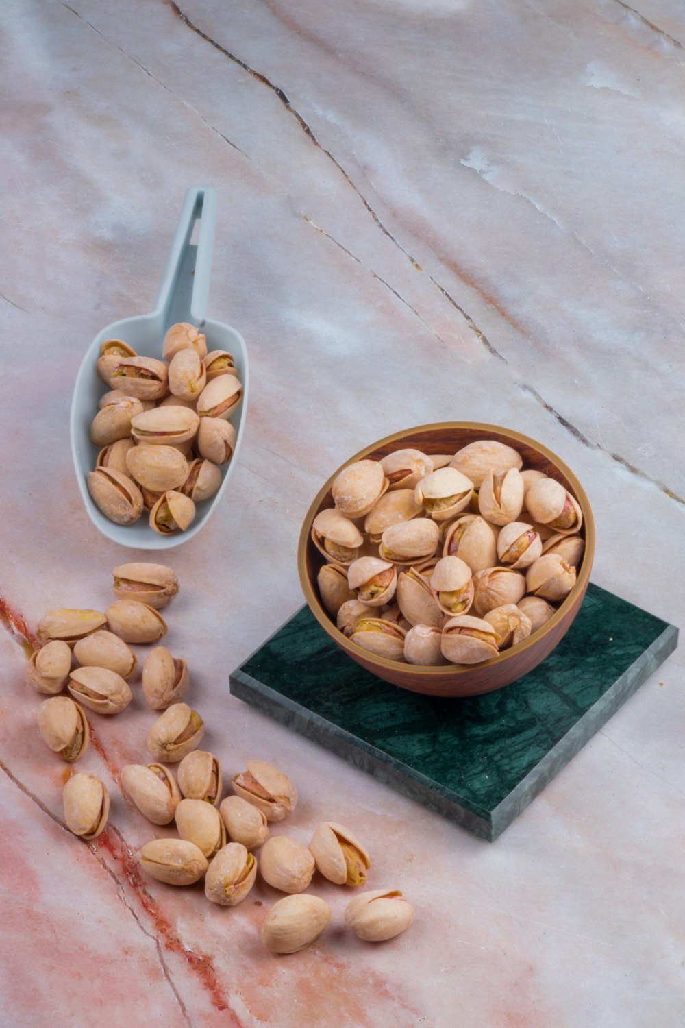 a bowl of nuts and a spoon on a marble surface