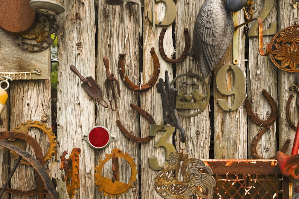 a wooden fence covered in assorted metal items