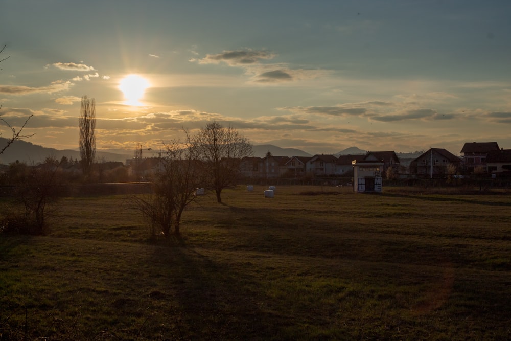 the sun is setting over a grassy field