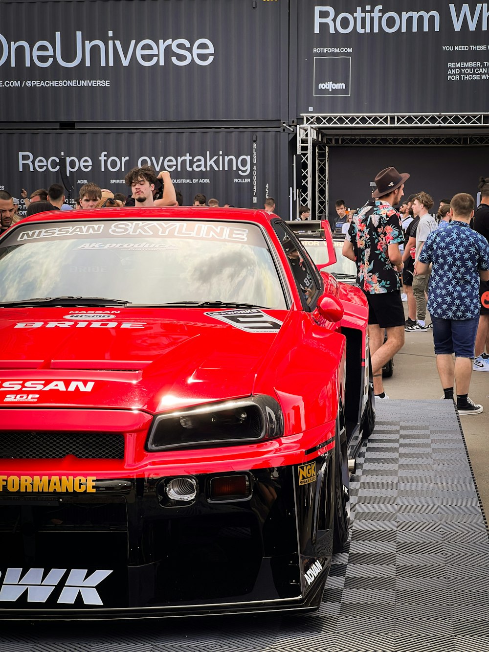 a red sports car parked in front of a crowd of people